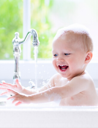 Infant bathing in tub water treated with quality water softening technology.